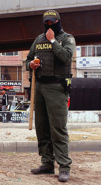Un policía porta un arma irreglamentaria, un bate, y se cubre el rostro para no ser identificado. Foto: Camila Ramírez.