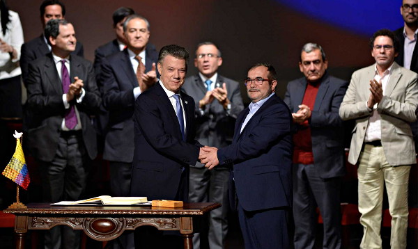 Juan Manuel antos y Rodrigo Londoño 'Timochenko' se dan la mano durante el acto de firma del acuerdo de paz en el Teatro Colón de Bogotá. Foto: Efraín Herrera, presidencia.