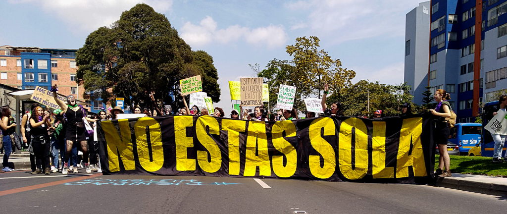 Marcha de mujeres con carteles y una pancarta que dice: "No estás sola". Foto: Andrea Umaña