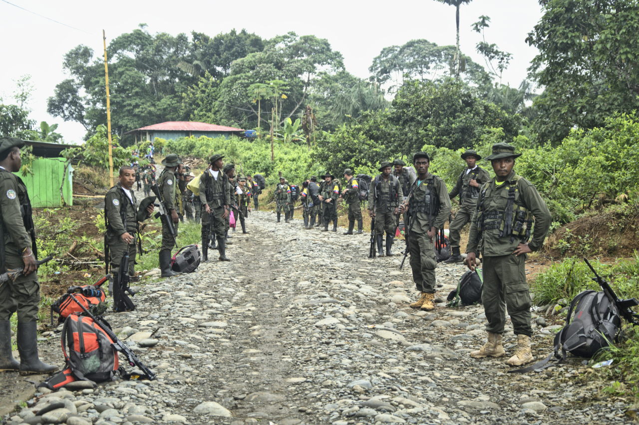 Dos filas de excombatientes descansan a lado y lado de la vía camino al punto de dejación de armas. Foto: Andrés Gómez.
