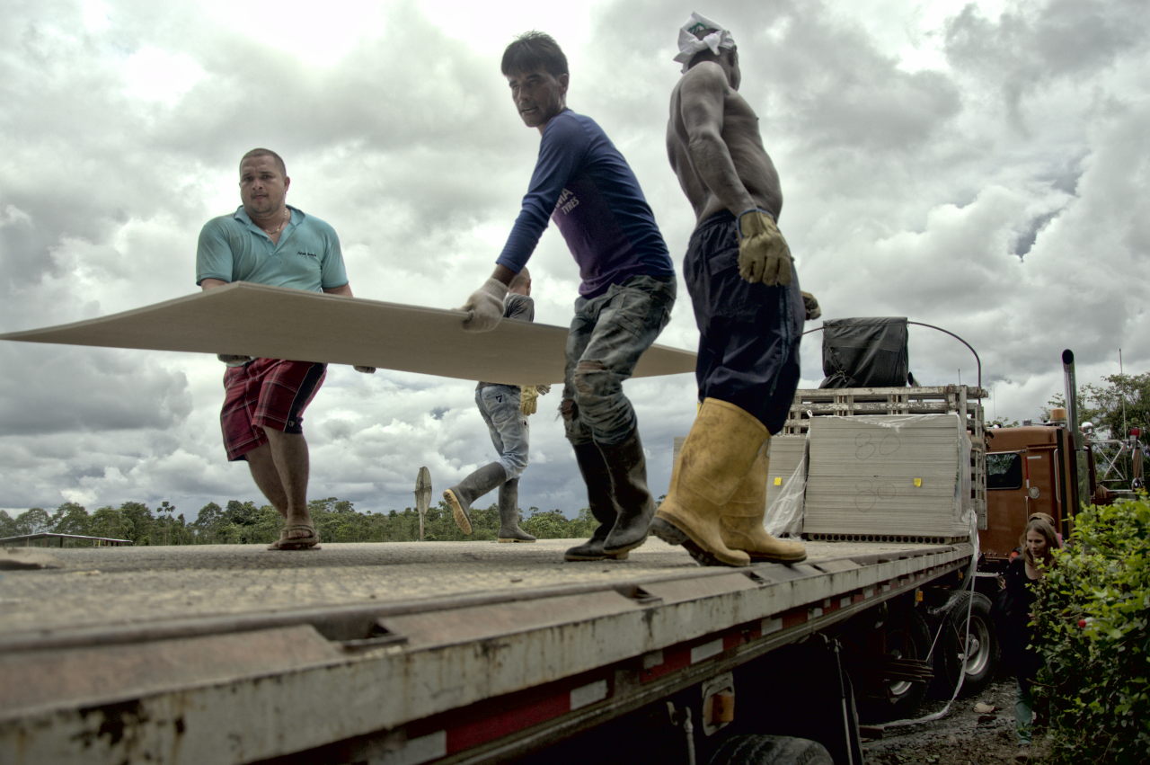 Cuatro obreros descargan de un camión las placas de construcción que debían servir para la zona veredal. Foto: Andrés Gómez.