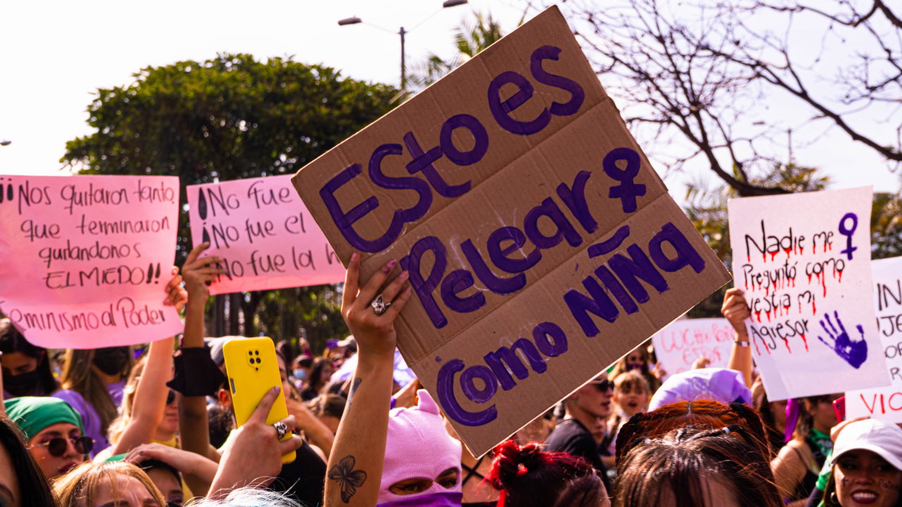 Mujeres en protesta levantan carteles, al centro uno con la inscripción "Esto es pelear como niña". Foto: María Paula Betancourt
