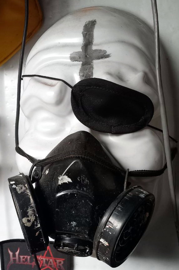 Una máscara blanca en resina con figura humana porta un parche en el ojo, una cruz pintada en la frente y un respirador sobre la nariz y la boca. Foto: Andrés Gómez