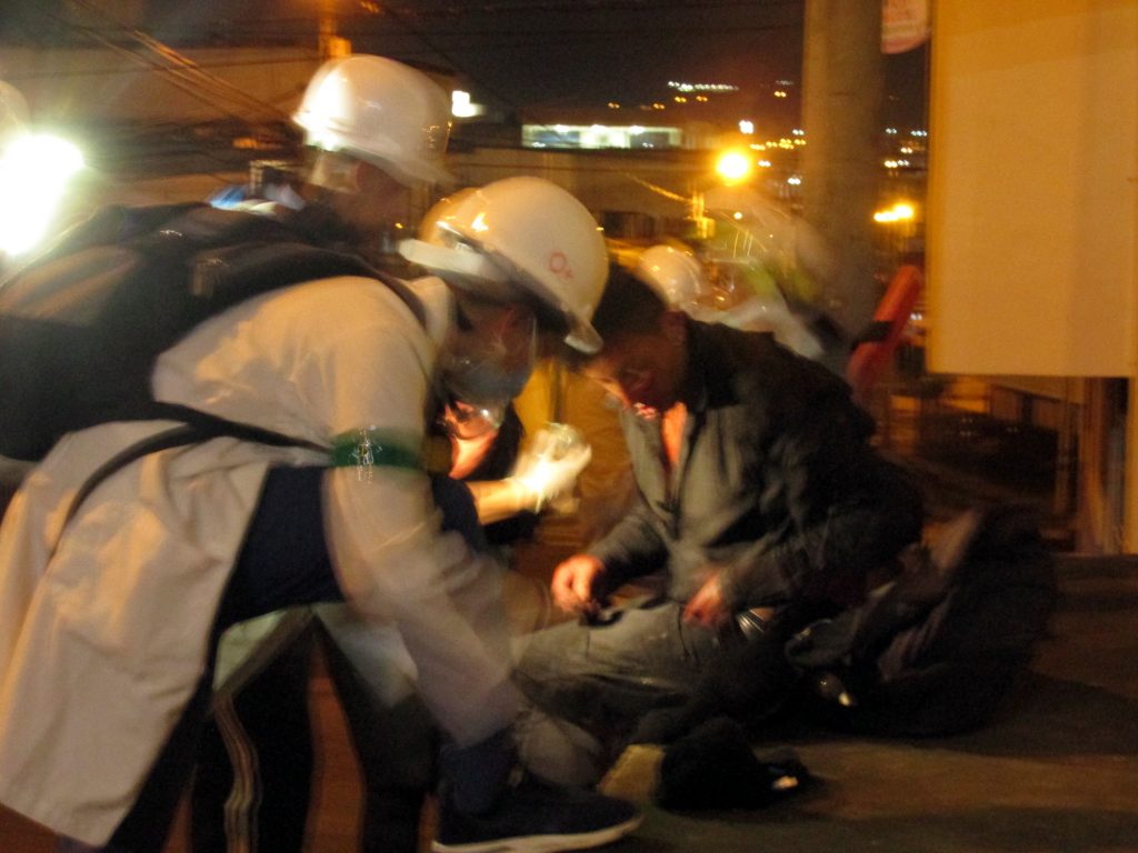 Dos socorristas de casco y bata blanca atienden a un herido. Foto: Andrés Gómez