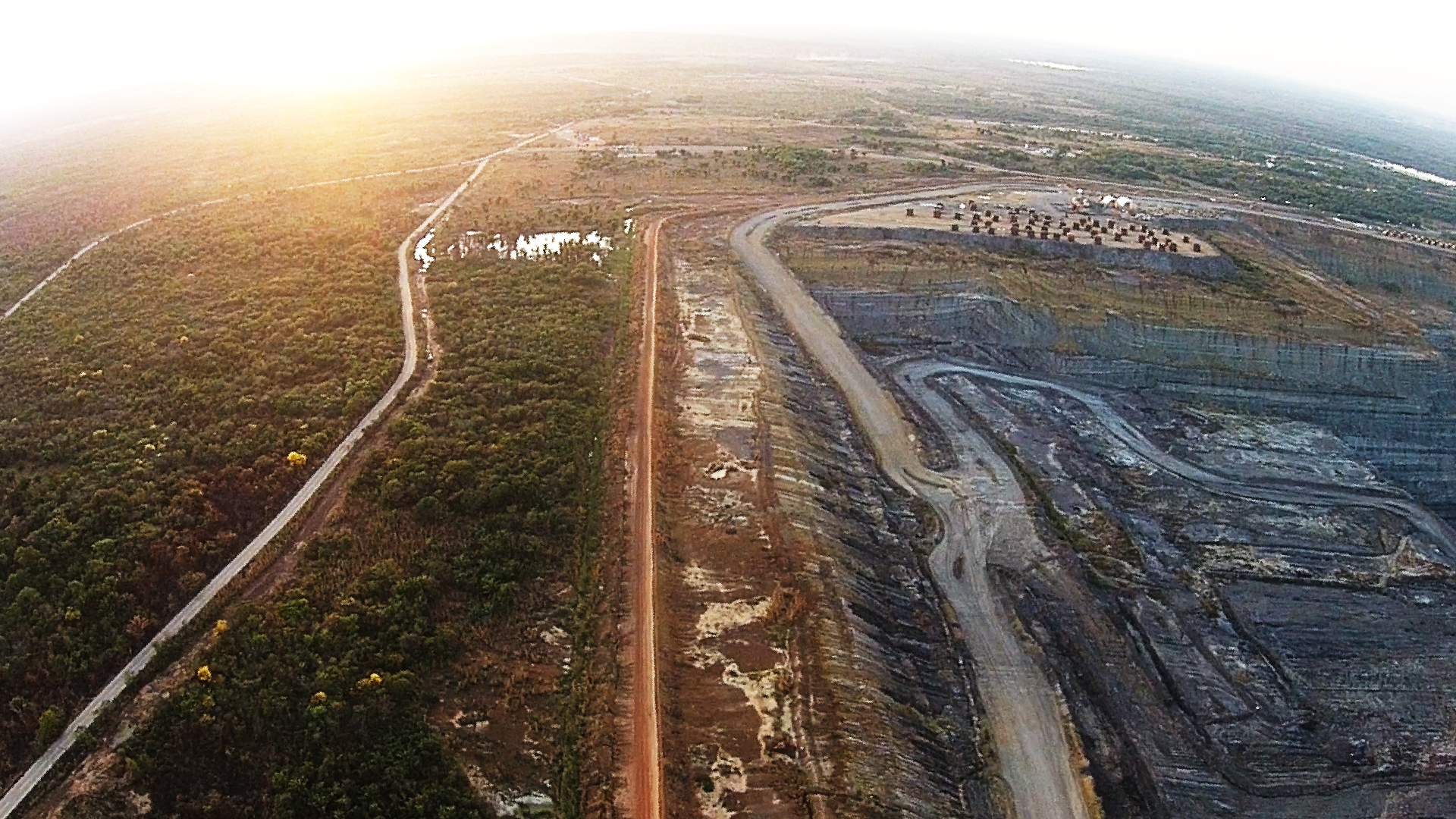 Vista aérea de la mina de Calenturitas en Cesar. Del lado izquierdo se ve parte de lo que queda del bosque tropical seco en la zona y del lado derecho uno de los pozos de extracción de carbón. Al fondo se ven estacionadas numerosas máquinas de minería.